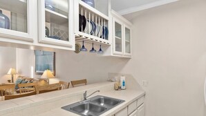 A kitchen with a double sink, white cabinets, and a dish rack above the counter.