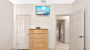 A hotel room with a wooden dresser, a television on the wall, and two beds.