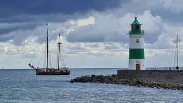 A lighthouse by the sea with a ship in the background.