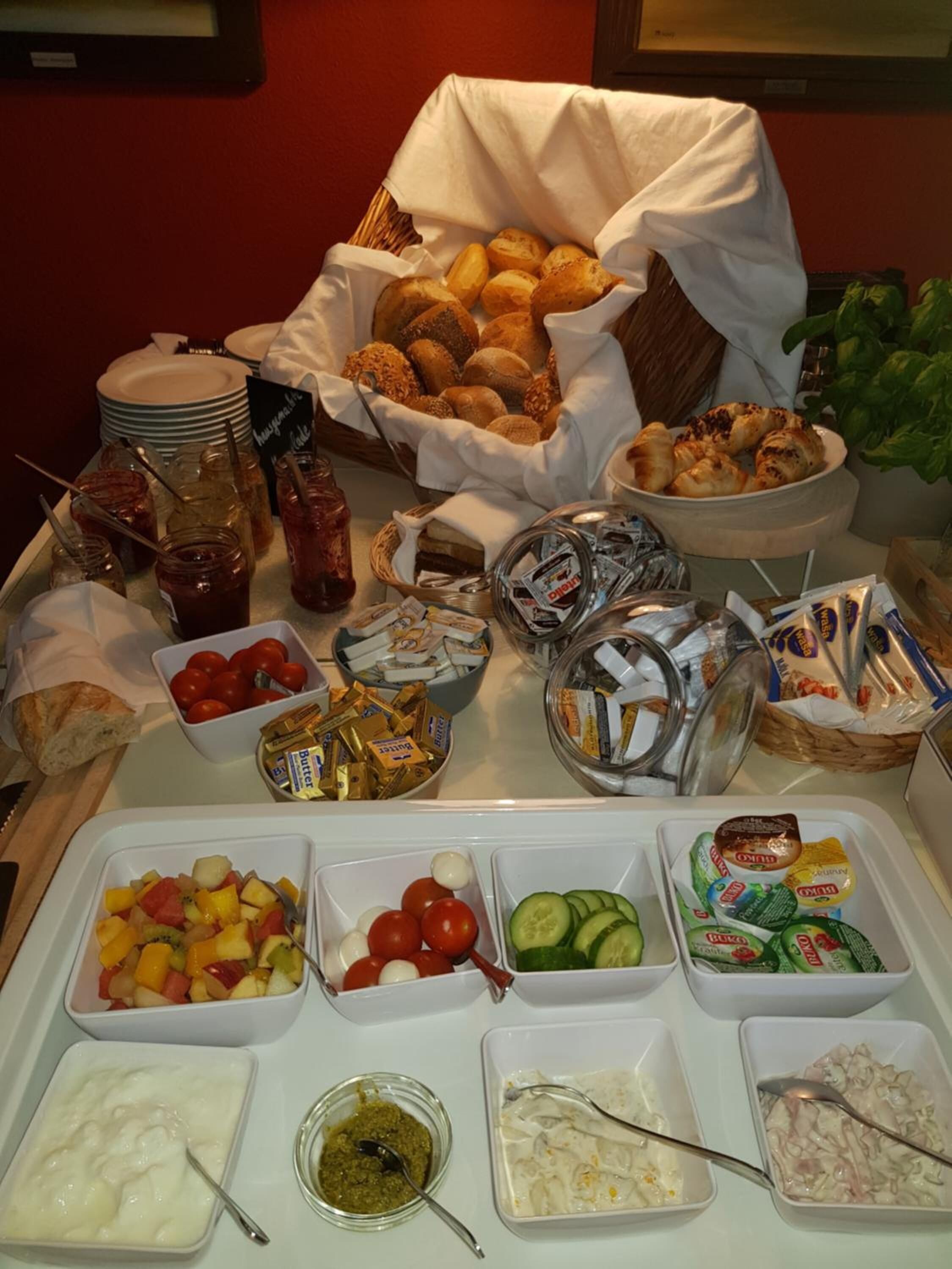 Un buffet proposant une variété d’aliments, notamment du pain, des pâtisseries, des fruits, des légumes et des condiments.