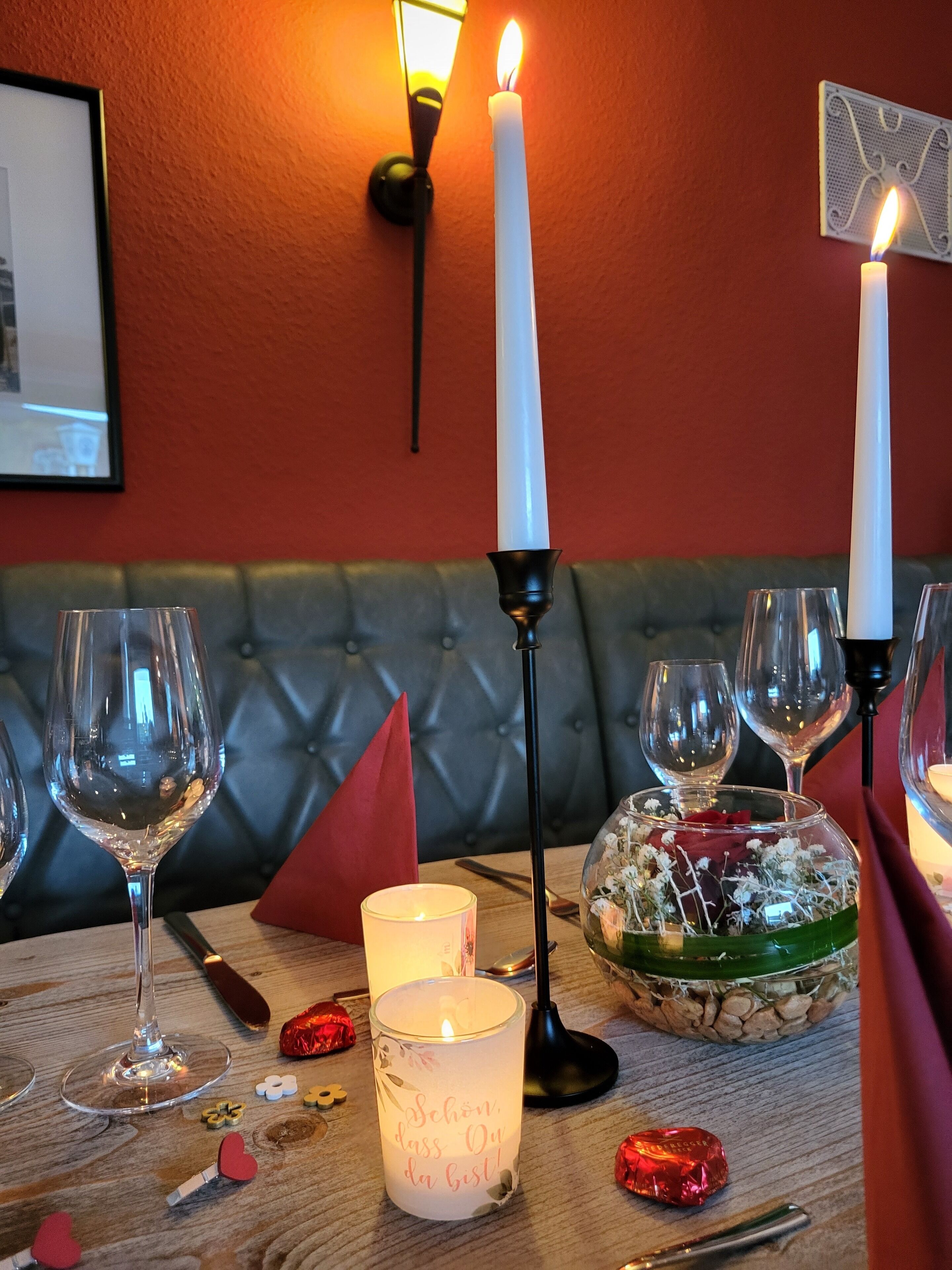 A table set with wine glasses, a candle, and a decorative bowl with flowers.