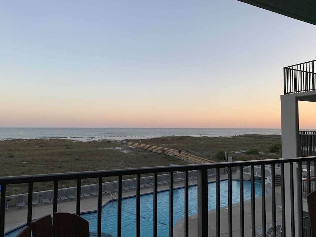 A pool area with a view of the beach and ocean.