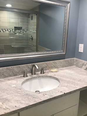 A bathroom with a marble sink, two faucets, and a large mirror. - Ocean One 306 - Oceanside prime beach location, walk to shops,dining, remodeled (Hilton Head Island)