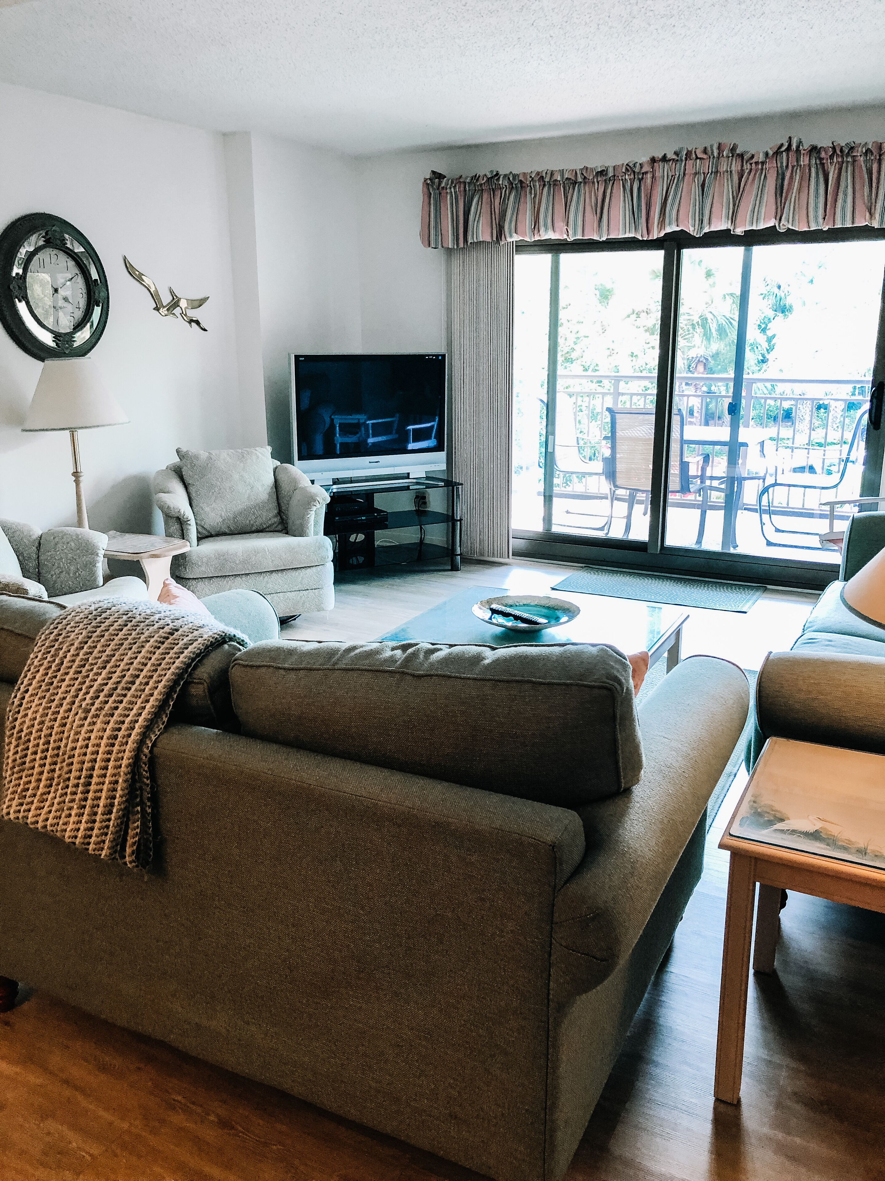Una sala de estar con sofá, sillón y televisor sobre un mueble.