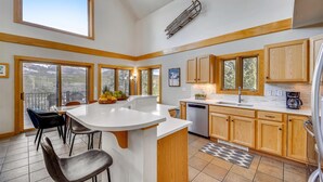 A modern kitchen with a large island, wooden cabinets, and a view of the outdoors. - Powder Moose Villa-Stunning Mountain Views from this Private Home with Hot Tub. (Breckenridge)