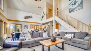 A spacious living area with a large gray sectional sofa, a wooden coffee table, and a staircase leading to an upper level. - Powder Moose Villa-Stunning Mountain Views from this Private Home with Hot Tub. (Breckenridge)