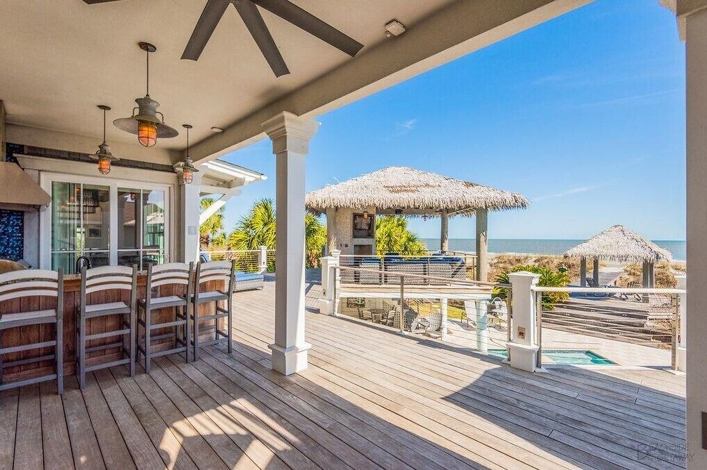 Eine Holzterrasse mit Sitzgelegenheiten und Blick auf den Strand.