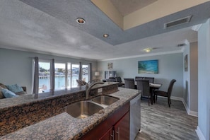 A modern kitchen with granite countertops, stainless steel sinks, and a dining area with a view.