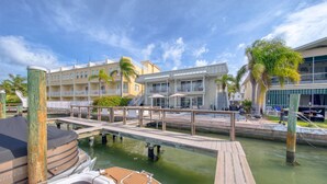 Una marina con un muelle, un barco y un edificio con balcones y terraza.