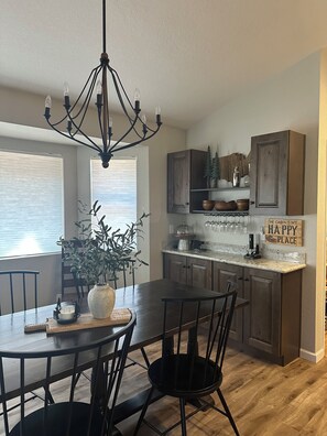 A dining area with a chandelier, a potted plant, and a table set for four.
