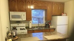 A kitchen with wooden cabinets, a microwave, stove, sink, and a refrigerator. - Estate Living! Professionally Cleaned, Self Check In - Sleeps 12 (Mt Pleasant)