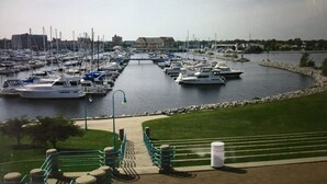 A marina with multiple boats docked, a grassy area with a pathway, and buildings in the background. - Estate Living! Professionally Cleaned, Self Check In - Sleeps 12 (Mt Pleasant)
