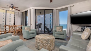 Ein geräumiger Balkon mit Deckenventilator, ein Essbereich mit Stühlen und Tisch sowie ein großer Flachbildfernseher.