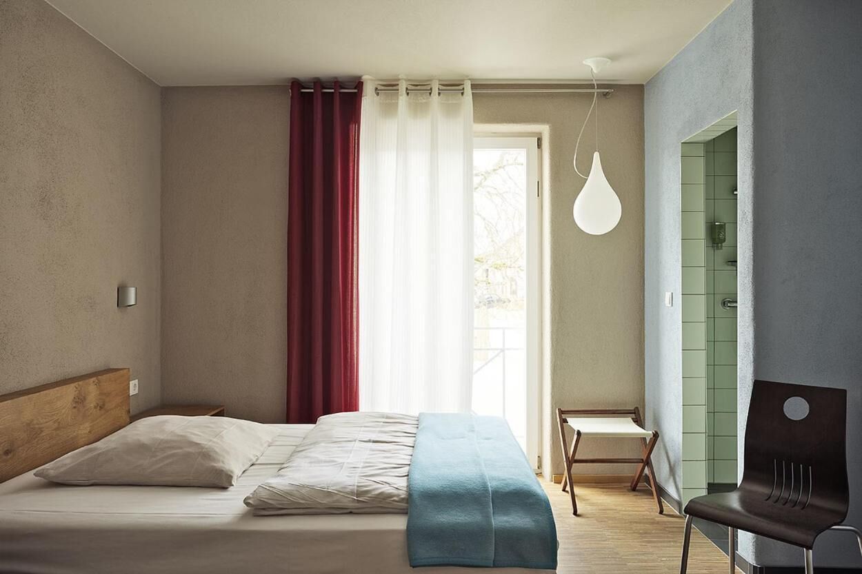 Una camera da letto con un letto, una sedia, una scrivania e una lampada a sospensione.