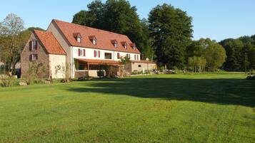 Un grand bâtiment à deux étages, doté d’un toit en pente, entouré d’une pelouse bien entretenue et d’arbres.