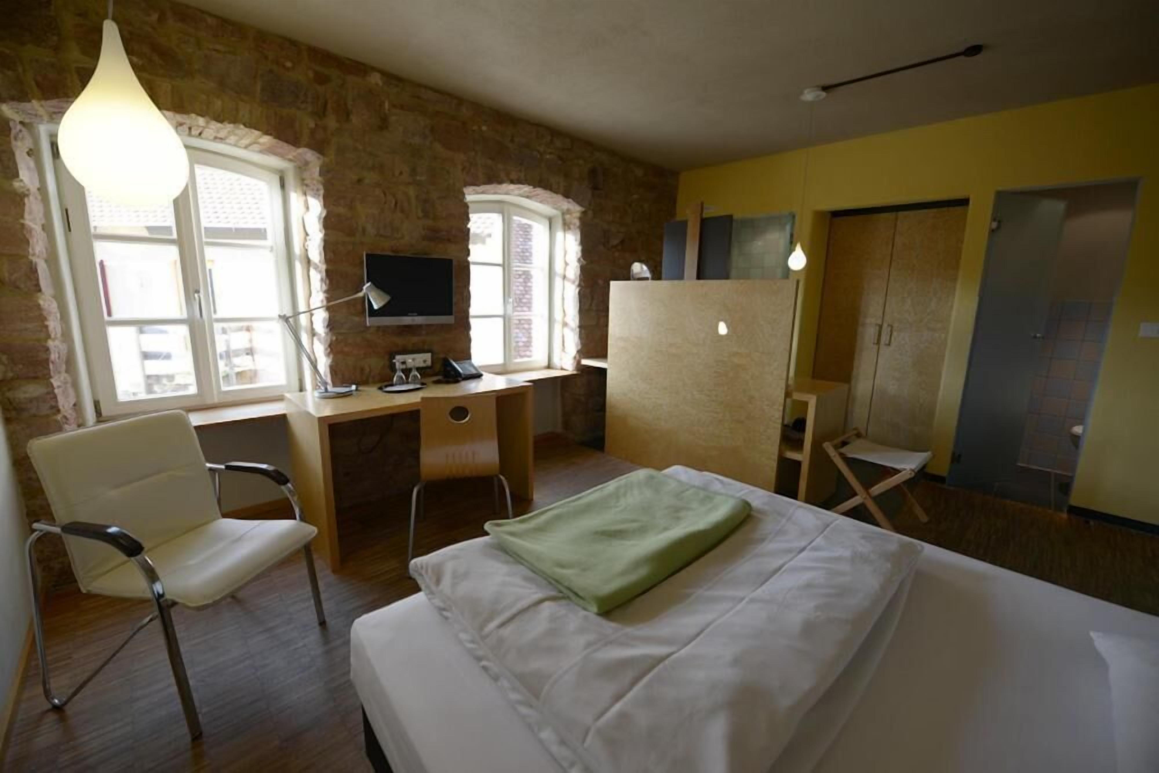 A room with a bed, a desk, a chair, a television, and a wardrobe.