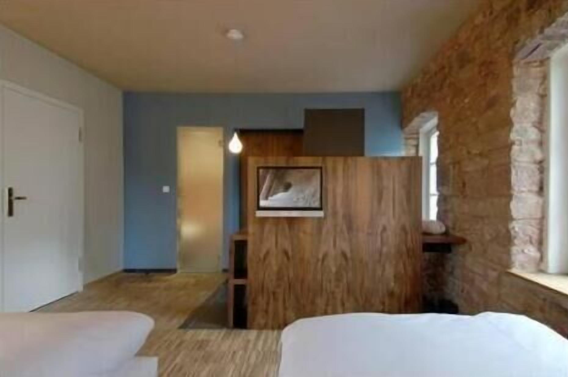 Een hotelkamer met een houten accentmuur, een lijst met een afbeelding en een raam.