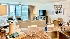 Una habitación de hotel moderna con sala de estar, kitchenette y ventanas amplias.