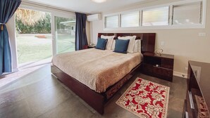 Een slaapkamer met een groot bed, een nachtkastje, een bureau en uitzicht op de omgeving.