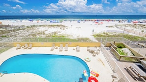 A pool area with lounge chairs and a view of the beach.