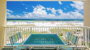 A balcony with a view of a beach, a pool table, and striped chairs.