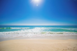 A beach with clear blue water and a sandy shore.