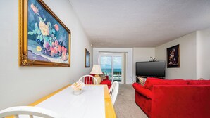 A living room with a dining table, red sofa, and a TV.