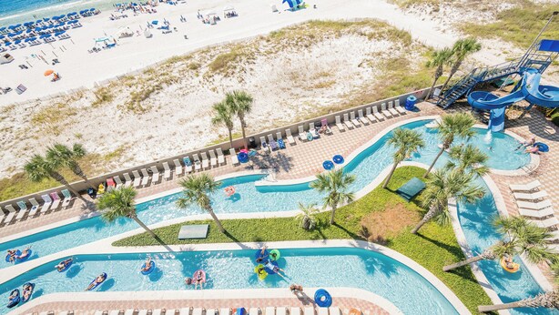 A resort with a pool area, lounge chairs, and a beach.