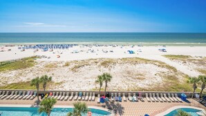 A beach view with a pool area, lounge chairs, and umbrellas.