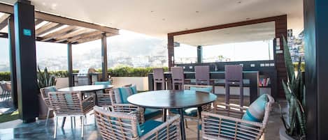 An outdoor patio with wicker furniture, a round table, and a grill.