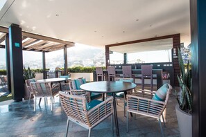 An outdoor patio with wicker furniture, a round table, and a grill.