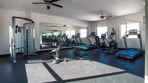 Un gimnasio con equipo de ejercicio, un ventilador de techo y un espejo grande.