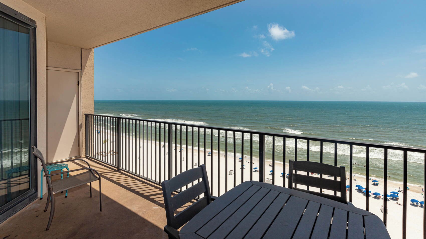 A balcony with a view of the beach and ocean.