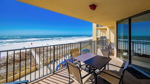 A balcony with a view of the beach and ocean.