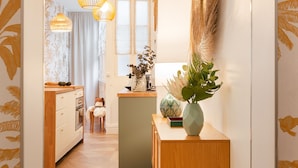 A hallway with wooden flooring, a wooden bench, and a wall-mounted decorative plant.