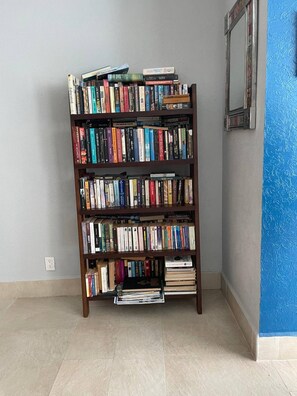 Ein Bücherregal voller Bücher in einem Raum mit gefliestem Boden und blauer Wand.