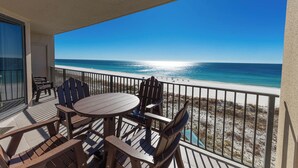 A balcony with a table and chairs overlooking a beach. - Phoenix X - 6th Floor - 3 Bedroom (Orange Beach)