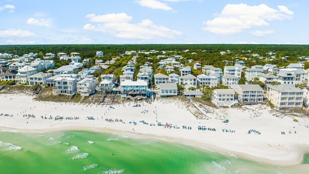 Eine Wohngegend an der Küste mit Häusern direkt am Strand, einem Sandstrand und blauem Himmel.