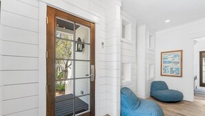 Ein Zimmer mit Holztür, weißen Wandverkleidungen, einem blauen Sitzsack und einem gerahmten Bild an der Wand.