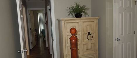 A hallway with a wooden cabinet, a plant on top, and a door on the right.