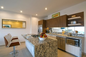 A modern kitchen with a marble countertop, stainless steel appliances, and a fruit bowl. - Top Floor Condo with City View, Rooftop Pool, Gym in Old Town (Puerto Vallarta)
