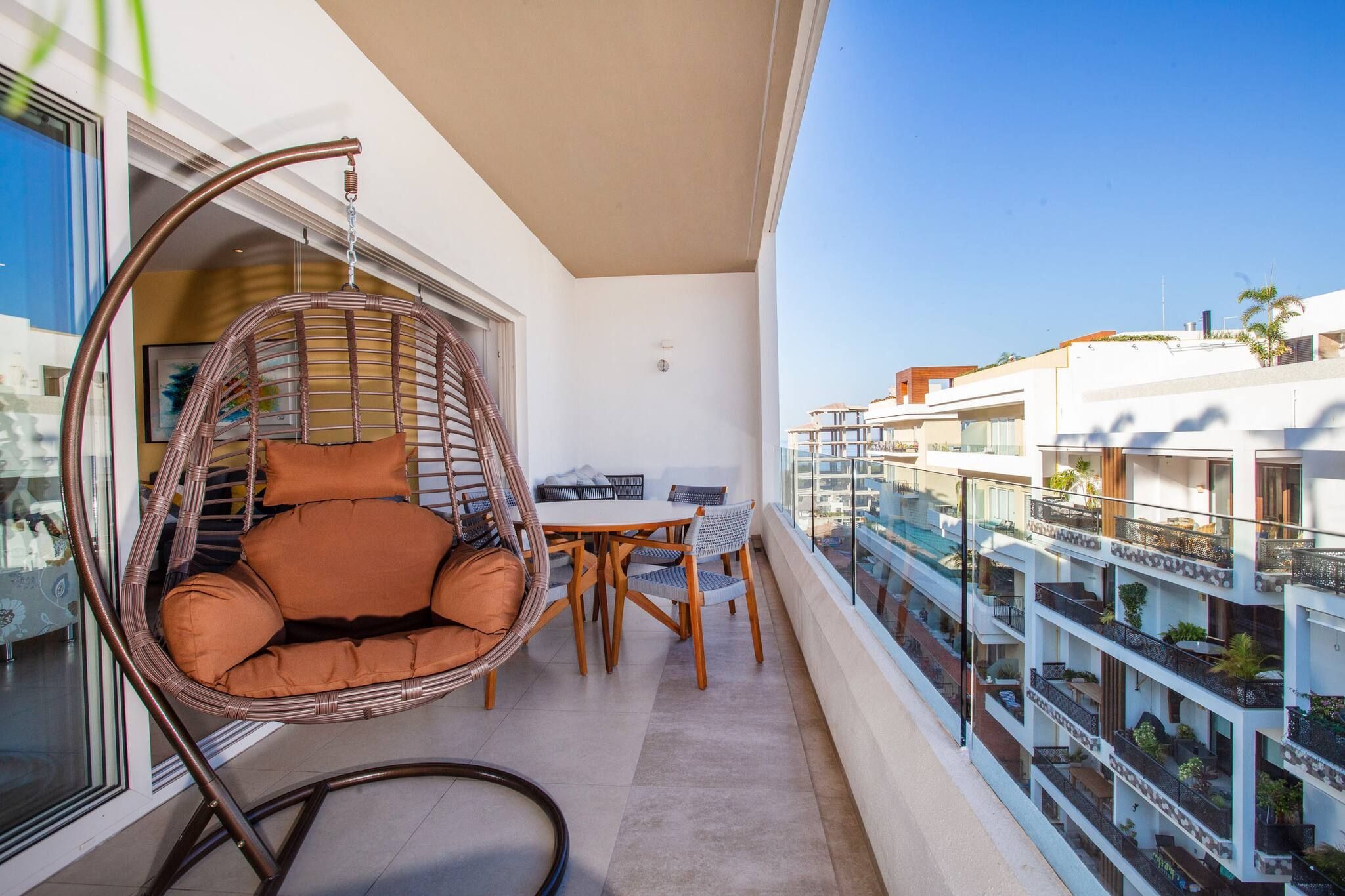 A balcony with a wicker chair, a dining table, and chairs.