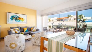 A modern living room with a sofa, coffee table, and a dining area with a glass table and chairs. - Top Floor Condo with City View, Rooftop Pool, Gym in Old Town (Puerto Vallarta)