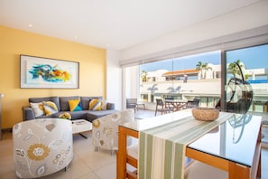A modern living room with a sofa, a coffee table, and a dining area with chairs and a table. - Top Floor Condo with City View, Rooftop Pool, Gym in Old Town (Puerto Vallarta)