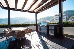 An outdoor patio with a wooden deck, a round table with chairs, and a built-in grill.