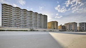 Een groot, meerlaags hotel met balkons, nabij een strand.