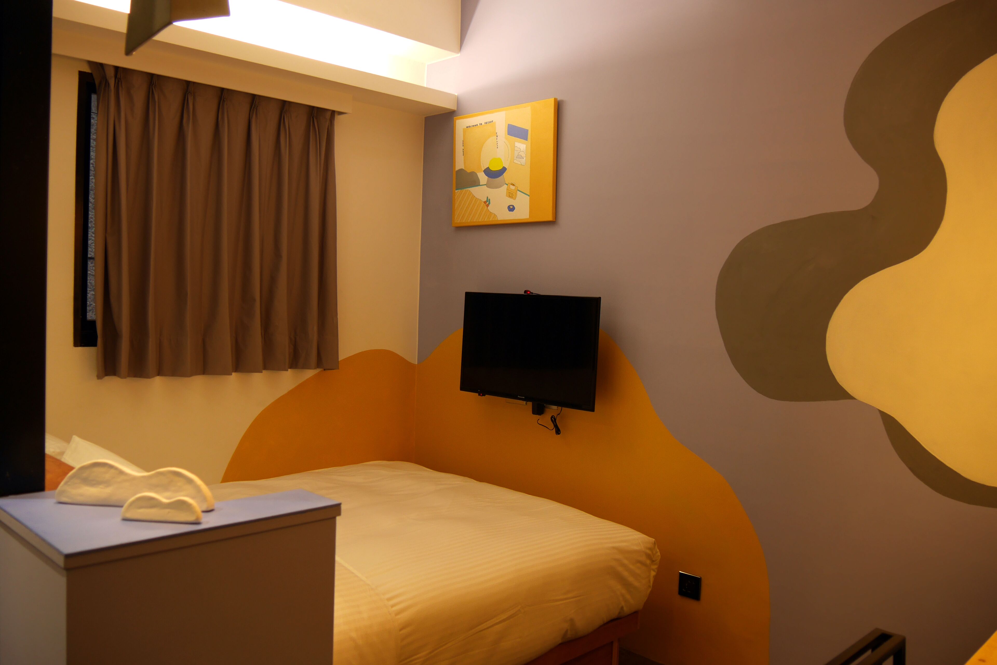Une chambre avec un lit, un bureau, une télévision et une fenêtre avec des rideaux.