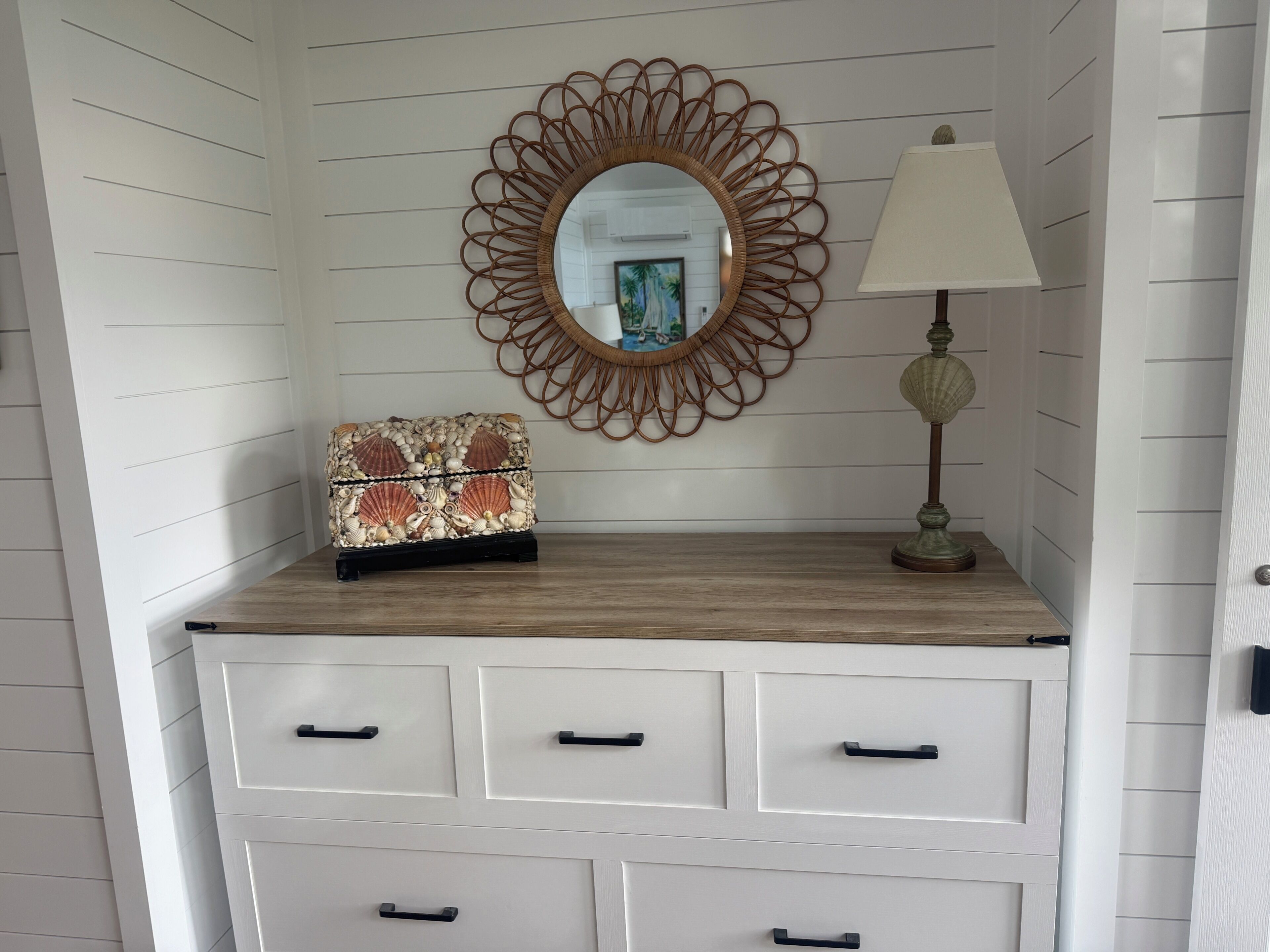 A dresser with drawers, a mirror, a lamp, and a decorative item on top.