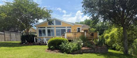 A house with a large deck, a well-maintained lawn, and a variety of plants.