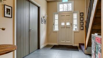 A hallway with a wooden bench, a door with a doormat, and a staircase.